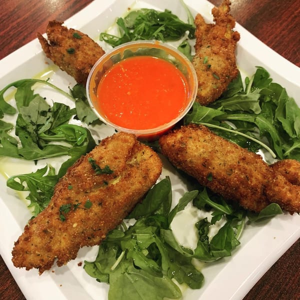 Four golden-brown fried mozzarella sticks with a side of red marinara sauce on a bed of arugula.