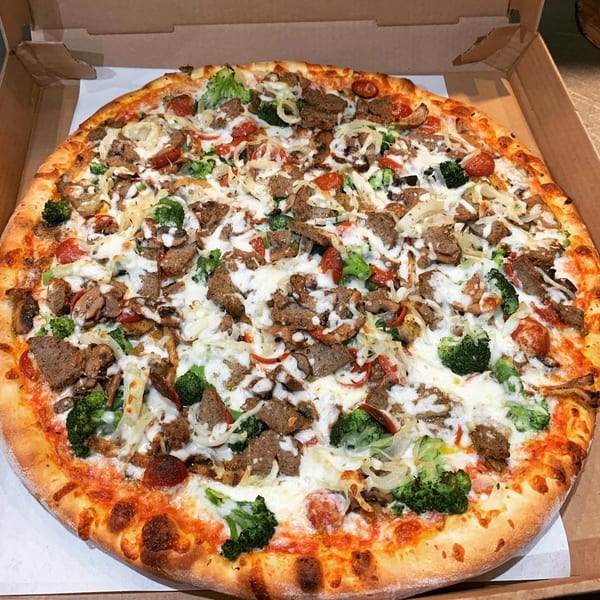Italiano Pizza & Food Co. pizza with steak, broccoli, onions, and white sauce in a box.